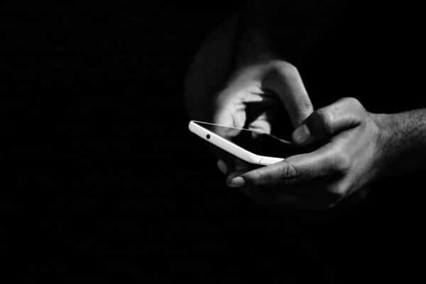 Des mains qui utilisent un smartphone dans l'obscurité