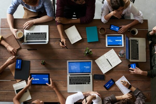 Une table vue du dessus avec 3 ordinateurs, 2 tablettes et beaucoup de smartphones