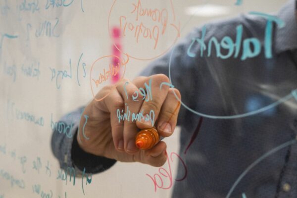 Un tableau transparent avec des formules écrites et une main en train d'écrire