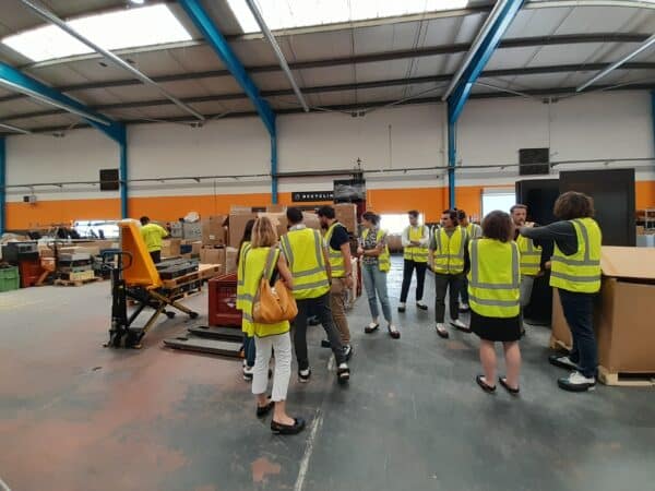 Un groupe d'une vingtaine de personnes en gilets jaunes visite un entrepot