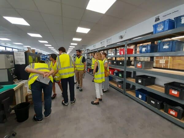 Une dame en gilet jaune explique à d'autres personnes en gilets jaunes le fonctionnement de l'entreprise