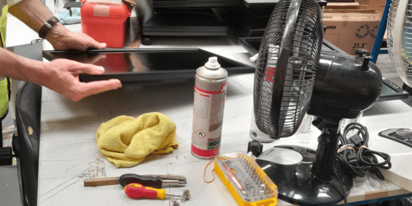 Des mains en train de réparer un écran avec des petits outils sur la table