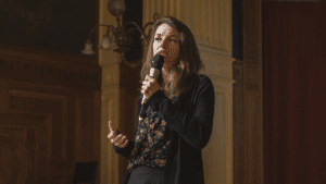 Laetitia Vasseur au micro dans une salle un peu sombre.