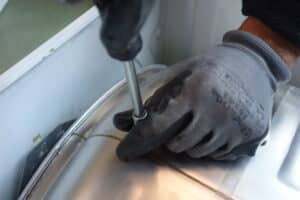 Métier de réparateur, personne avec un gant qui utilise un tourne vis