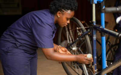Une réparatrice met de l'huile sur une chaine de vélo